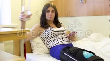 受伤的小女孩在医院里用手机喝水